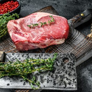 Raw beef club steak. Black ground. Top view. Copy space